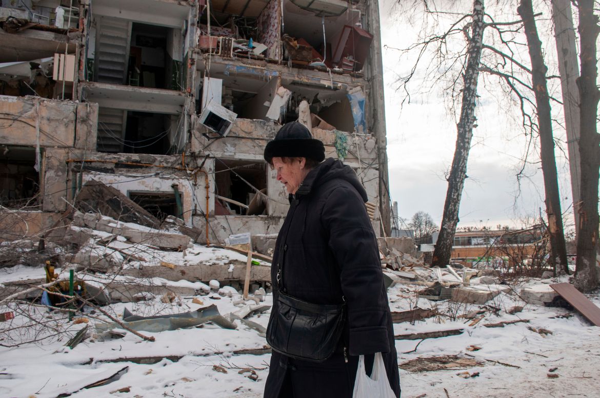 A woman walks past building damaged by shelling, in Kharkiv,