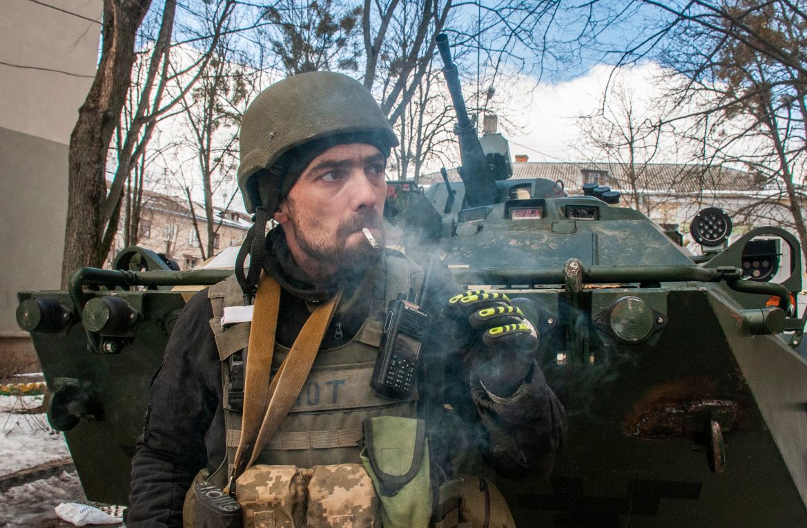 A volunteer of the Ukrainian Territorial Defense Forces stands next to his APC in Kharkiv