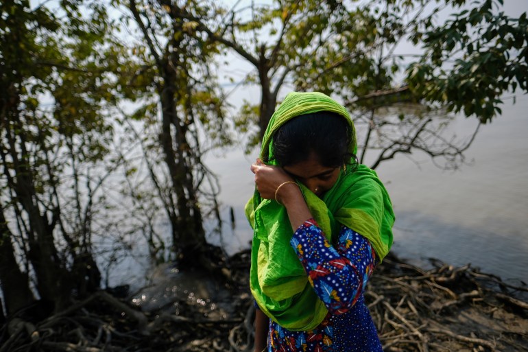 Reshma Begum, 28, wipes her tears as she stands on her lost land