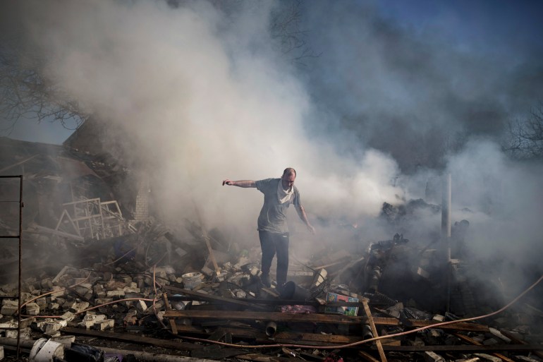 A man is seen walking on the debris of a destroyed house in Kharkiv