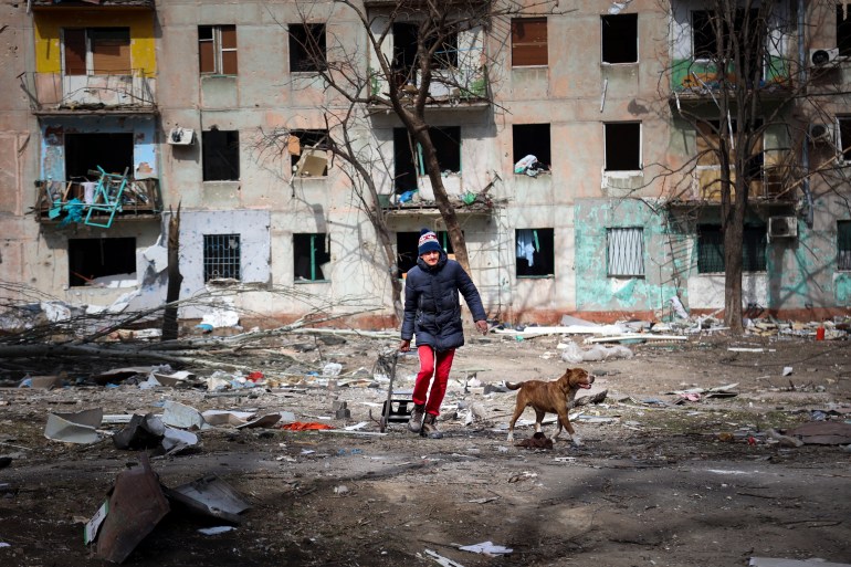 A man is seen walking near a ruined apartment block on the outskirts of Mariupol