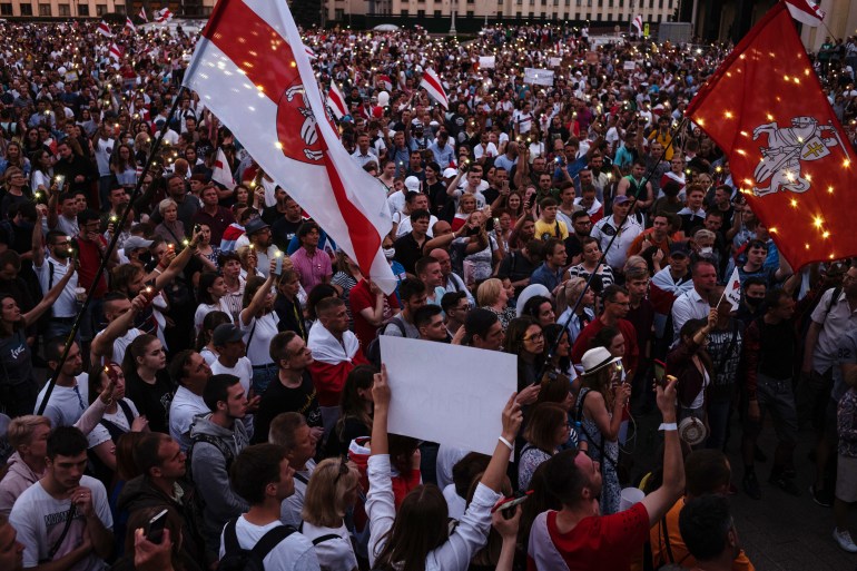 A photo of a large group of people at a rally holding Belarus flags and signs.