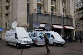 White media vans with satellites and journalists are seen outside a hotel in Kyiv, Ukraine