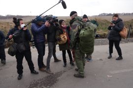 Members of the media interviewing a British volunteer preparing to enter Ukraine from Poland to fight alongside Ukrainians against the Russian army at the Medyka border crossing on March 3, 2022 at Medyka, Poland. [Sean Gallup/Getty Images]