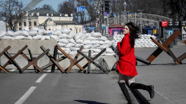 A woman runs across the street next to an anti-tank constructions in central Kyiv.
