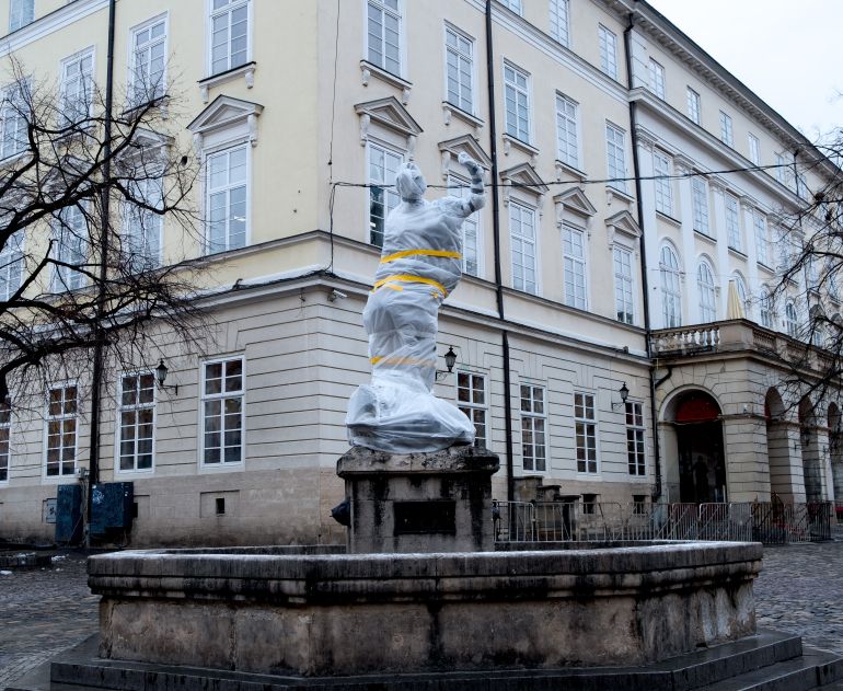 A photo of a statue covered in plastic wrap and tape in a town in Lviv.