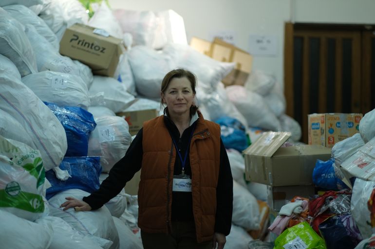 A woman standing in front of a large pile of white garbage bags and boxes.