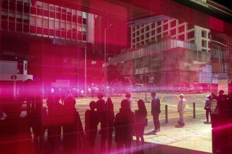 Pedestrians reflected in an electronic screen displaying stock figures in Hong Kong,