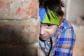 A frightened boy hides behind a wall in a basement in Kharkiv