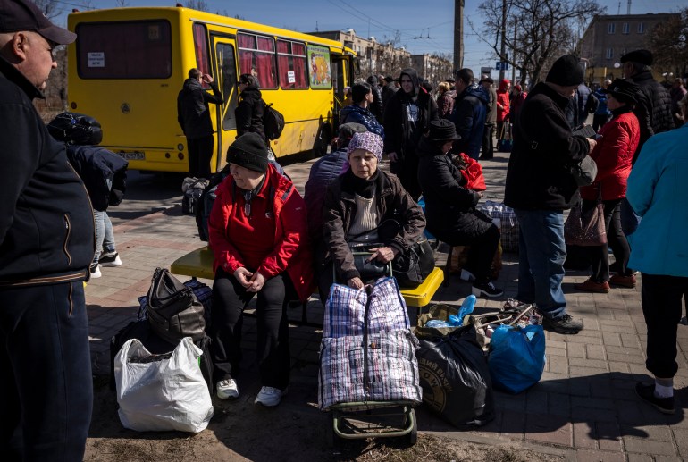 People wait for a bus to go in a train station in Severodonetsk, eastern Ukraine, on April 7, 2022, as they flee the city in the Donbas region