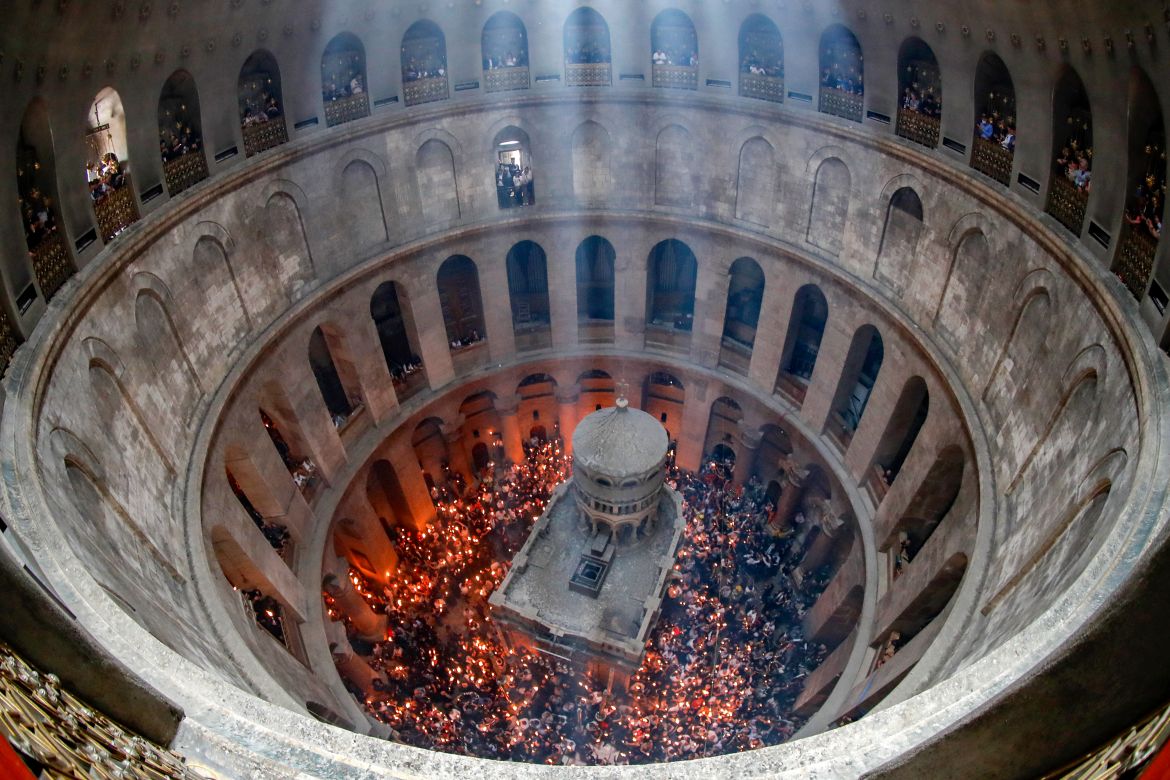 Orthodox Christians gather with lit candles around the Edicule
