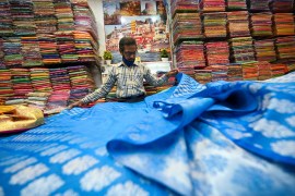 a shopkeeper shows a traditional Banarasi sari at a store in Varanasi, India