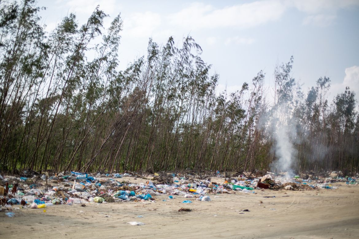 A photo of the Tam Hai shoreline littered with trash and burning waste.