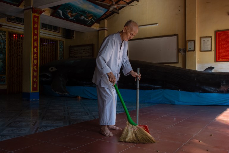 A photo of the elderly caretaker of Vung Tau’s whale temple sweeping the grounds.