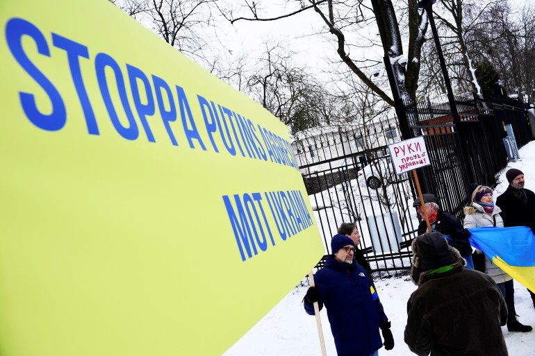 A protester holds a banner in front of the Russian embassy in Stockholm