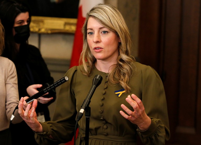Canadian Foreign Minister Melanie Joly speaks to reporters at a microphone