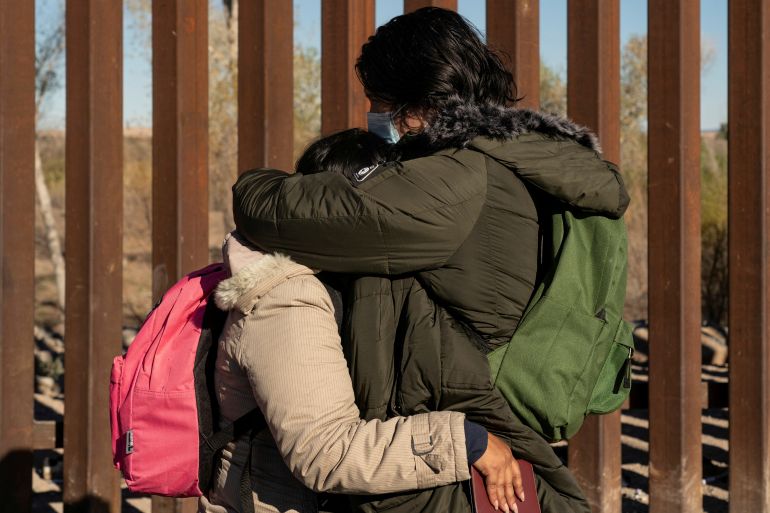 Asylum seekers hug near the US-Mexico border wall
