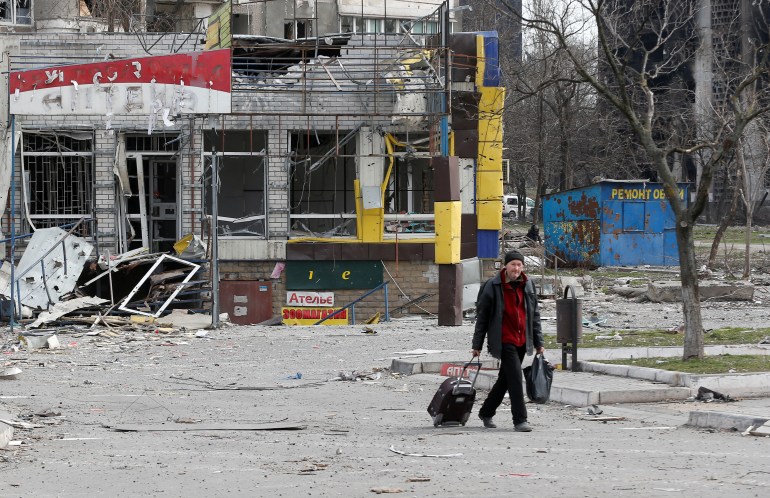 A man walks near a building damaged in the course of Ukraine-Russia conflict in the southern port city of Mariupol.