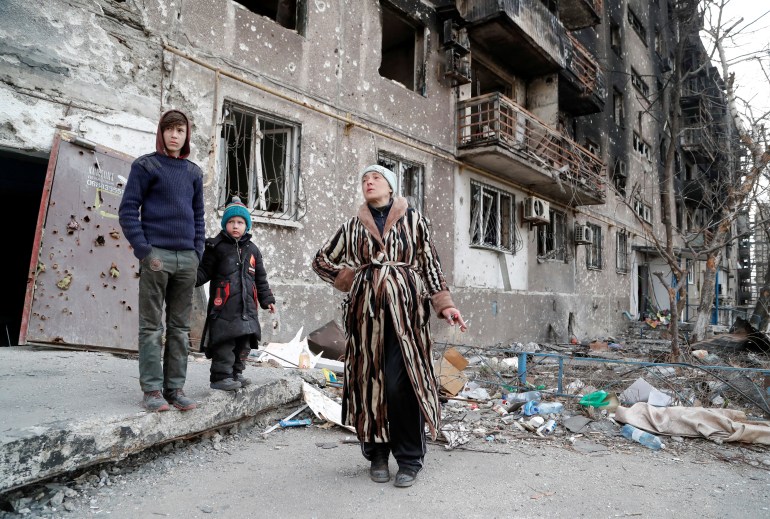 The Bykovets family members, Olga, 42, Ilya, 13, and Yegor, 5, who seek refuge in abandoned apartments of a residential building damaged in the course of Ukraine-Russia conflict, gather in a courtyard in the southern port city of Mariupol