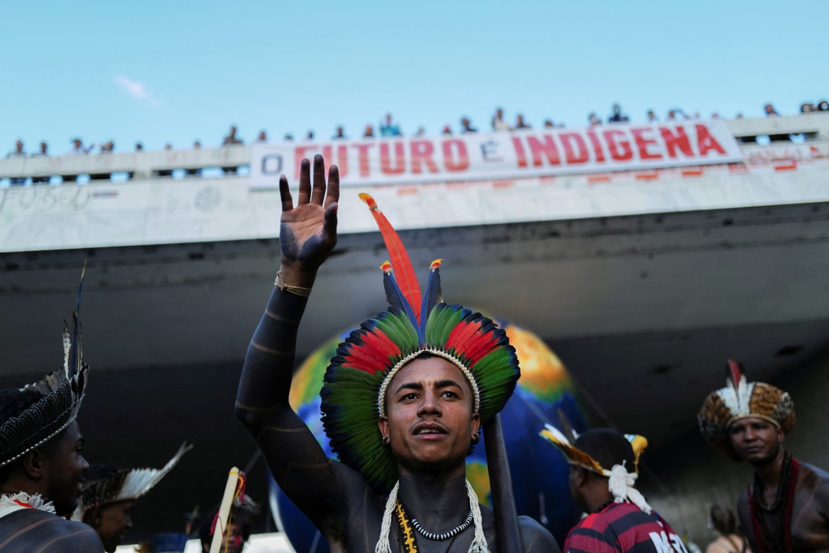 Indigenous people march in front of a banner that reads "the future is indigenous"