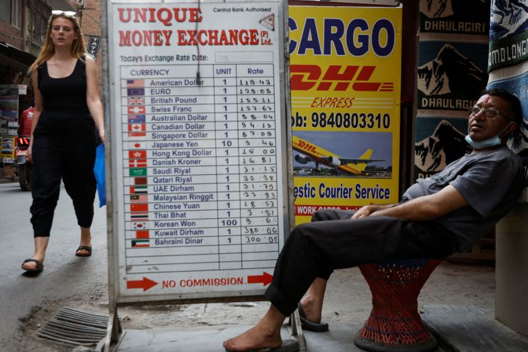 A man sits outside a money exchange at Thamel, a major tourist hub in Kathmandu, Nepal