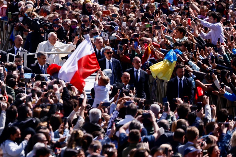 Polish and Ukrainian flags wave among the crowd as Pope Francis greets the faithful from his Popemobile in Saint Peter's Square