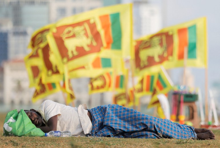 A man sleeps as Sri Lankan national flags are seen near Gota-Go village where the protestors gather during a protest against Sri Lanka President Gotabaya Rajapaksa in front of the presidential secretariat, amid the country's economic crisis in Colombo, Sri Lanka, April 19, 2022