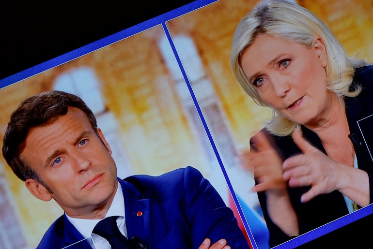 Marine Le Pen, shown in a TV screen, makes a point as Emmanuel Macron listens
