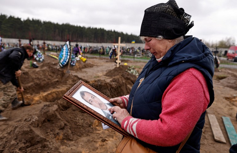 Natalia Maznichenko, 57, holds a photograph of her husband Vasyl Maznichenko, 61, who according to her was killed during Russian shelling on their building, as she mourns him during his funeral, amid Russia's invasion of Ukraine, at the cemetery in Bucha, 