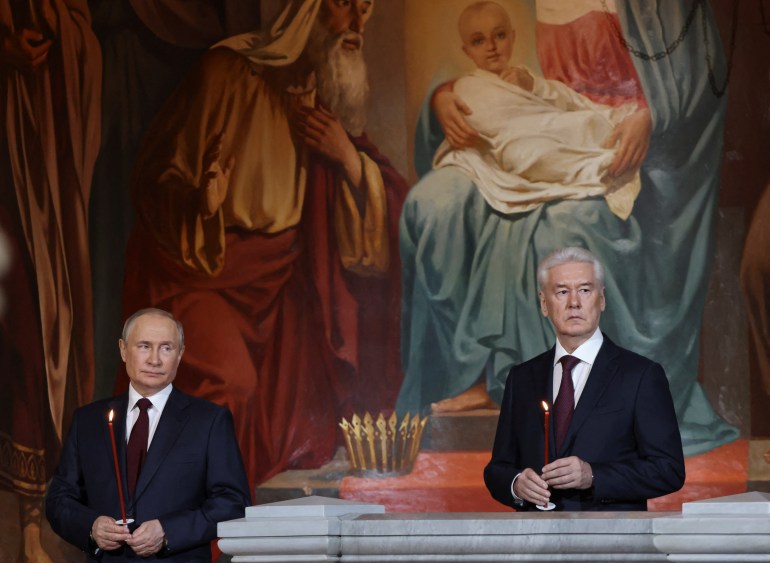 Russian President Vladimir Putin and Moscow's Mayor Sergei Sobyanin hold candles as they attend the Orthodox Easter service at the Cathedral of Christ the Saviour in Moscow