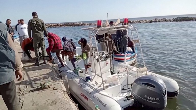 Migrants are helped off boat and onto shore