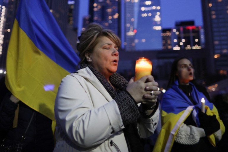 A woman holds a candle as she sings the national anthem of Ukraine during a candlelight vigil for Ukraine on the Orthodox Holy Saturday, at Nathan Phillips Square in Toronto, Ontario, Canada