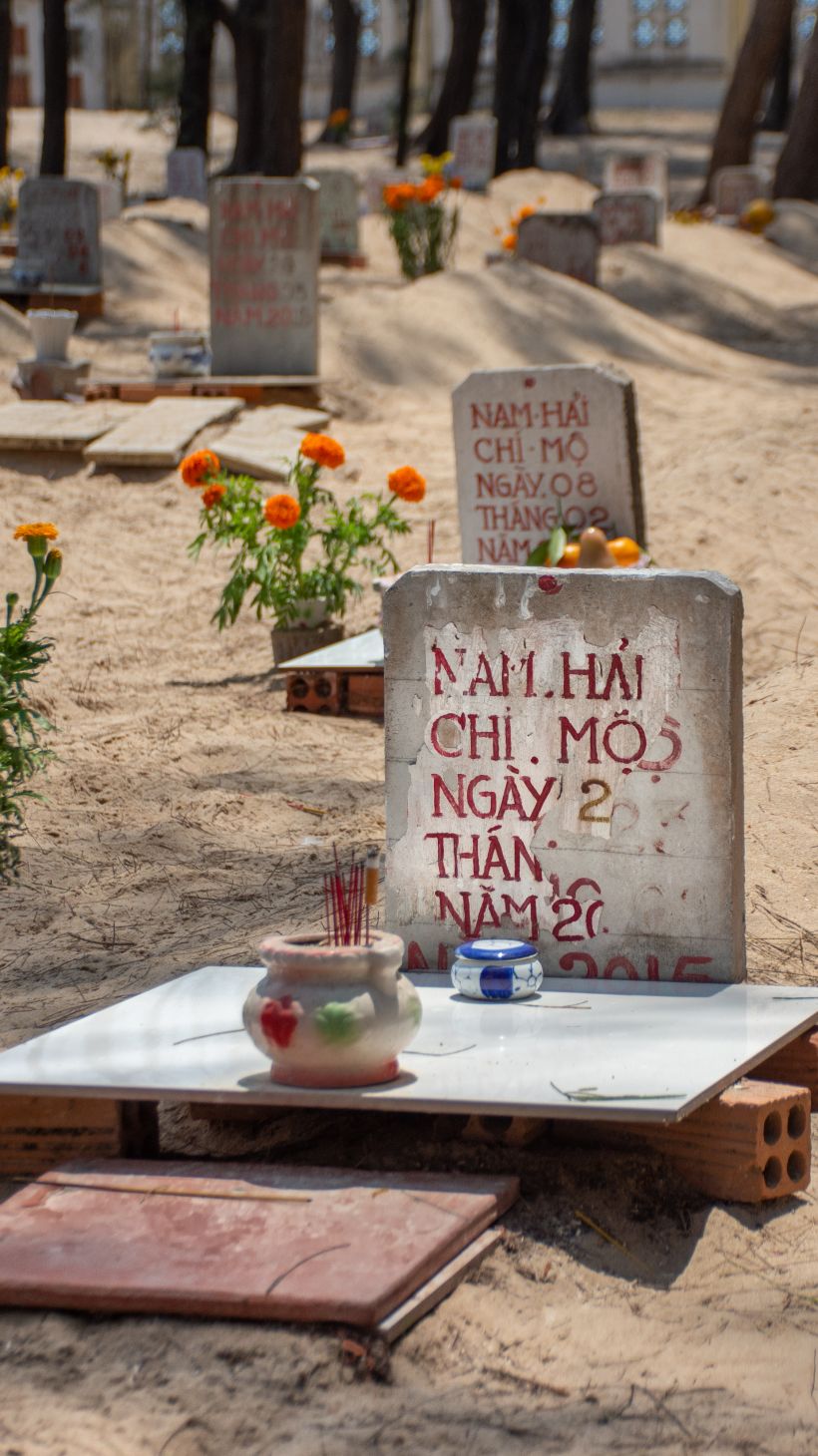 A photo of Phuoc Hai’s whale graveyard, a few dozen graves rise in little hillocks in the sand with headstones displaying the name of the fisherman that found the whale, the boat’s registration number, and the date of death.