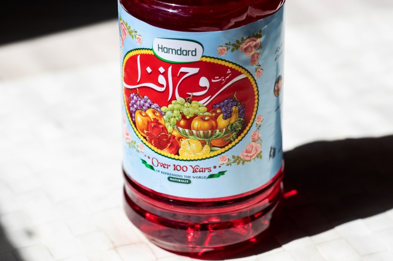 A closeup of the label of a rooh afza bottle, under the image of brightly coloured fruits is the slogan "over 100 years of refreshing the world naturally"