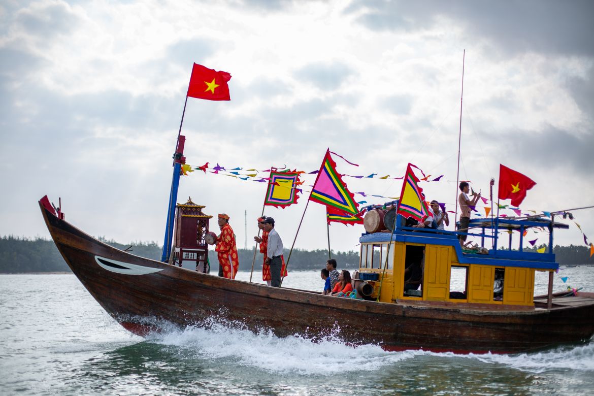 A photo of a a temple boat bedecked with brightly coloured bunting and an altar