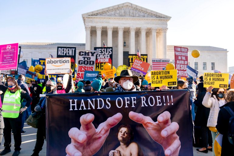 Stephen Parlato of Boulder, Colo., holds a sign that reads "Hands Off Roe!!!" as abortion rights advocates and anti-abortion protesters demonstrate in front of the U.S. Supreme Court.