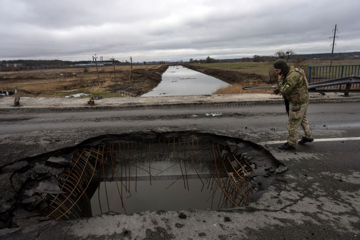 A Ukrainian soldier looks at a damaged bridge in Bucha