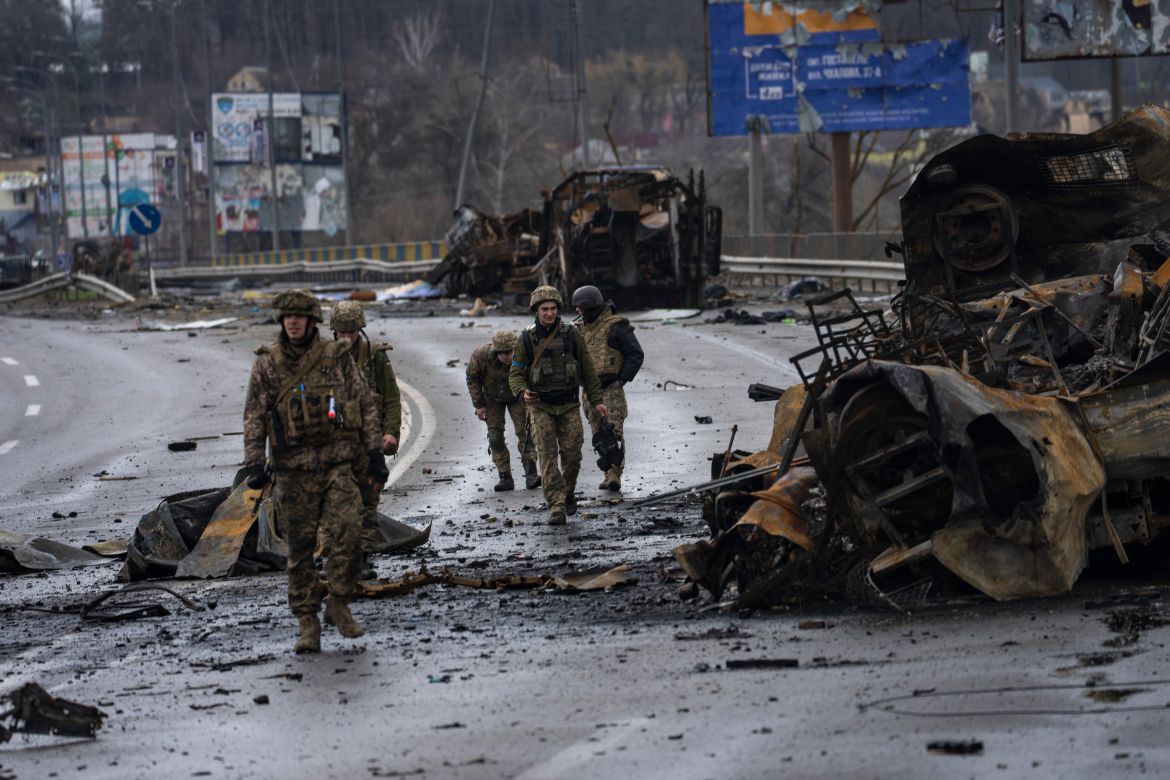 Ukrainian soldiers walk next to destroyed Russians armored vehicles