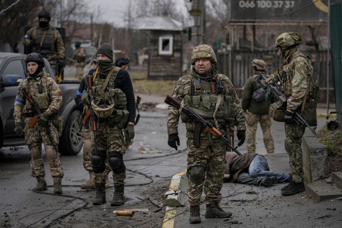 Ukrainian servicemen stand next to the body of man