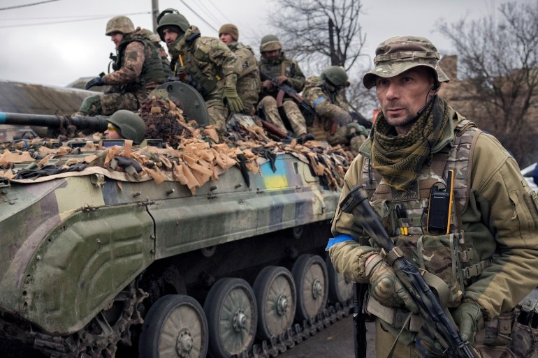 A Ukrainian serviceman walks next to a fighting vehicle, outside Kyiv.