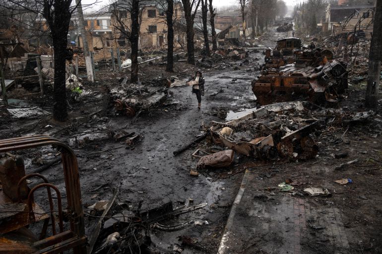 A woman walks amid destroyed Russian tanks in Bucha, on the outskirts of Kyiv
