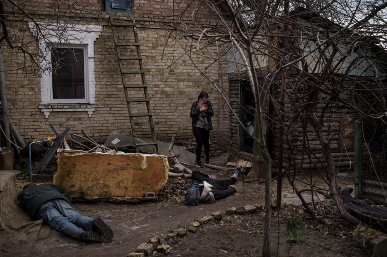 Ira Gavriluk holds her cat as she walks among the bodies of her husband, brother, and another man, who were killed outside her home in Bucha, on the outskirts of Kyiv, Ukraine, Monday, April 4, 2022. 