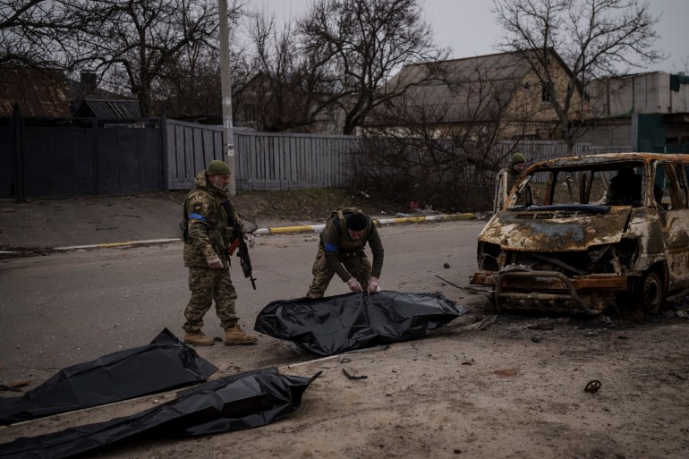 Ukrainian soldiers recover the remains of four killed civilians from inside a charred vehicle in Bucha, outskirts of Kyiv, Ukraine, Tuesday, April 5, 2022. 