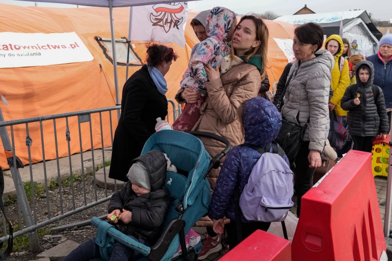 Refugees wait in a line after fleeing the war from neighboring Ukraine at the border crossing in Medyka, southeastern Poland, Sunday, April 10, 2022.