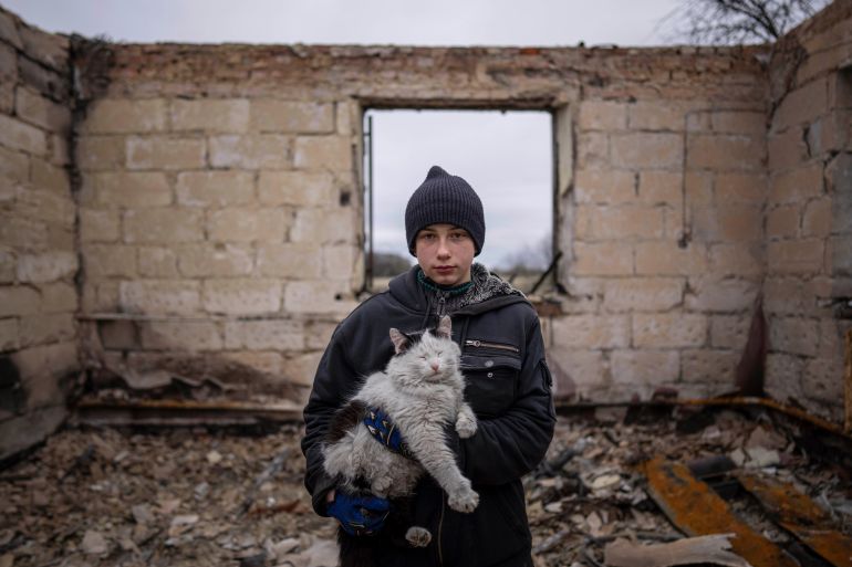 Danyk Rak, 12, holds a cat standing on the debris of his house destroyed by Russian forces' shelling in the outskirts of Chernihiv, Ukraine, Wednesday, April 13, 2022. After shelling Danyk's mother Liudmila Koval had to have her leg amputated and was injured in her abdominal cavity. She is still waiting for proper medical treatment. (AP Photo/Evgeniy Maloletka)