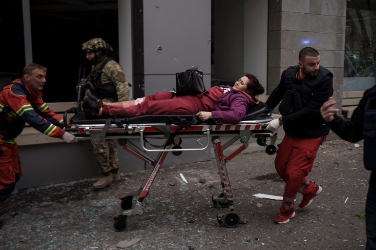A woman is taken to an ambulance after being injured in a Russian bombardment in Kharkiv