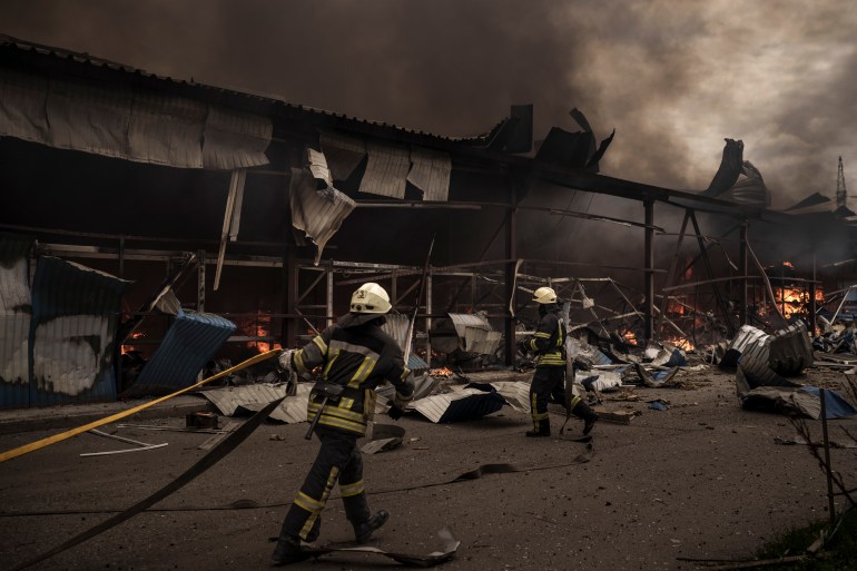 Firefighters work to extinguish a fire in a warehouse amid Russian bombardment in Kharkiv, Ukraine