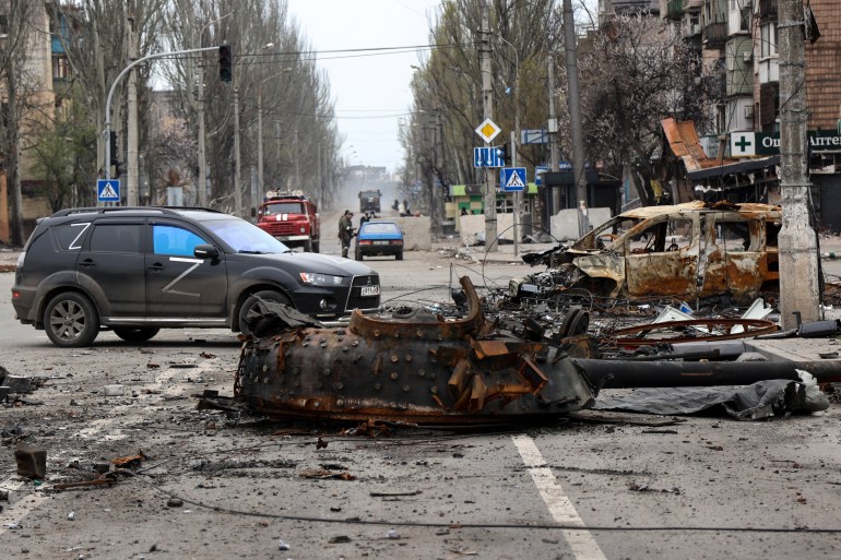 Part of a destroyed tank and a burned vehicle in the street