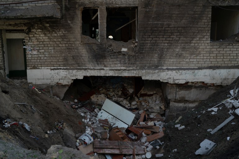 A crater from an explosion is seen next to a heavily damaged apartment and a basement of a residential building that killed, according to the residents, a 8-year-old girl during a Russian attack yesterday, in Lyman, Ukraine