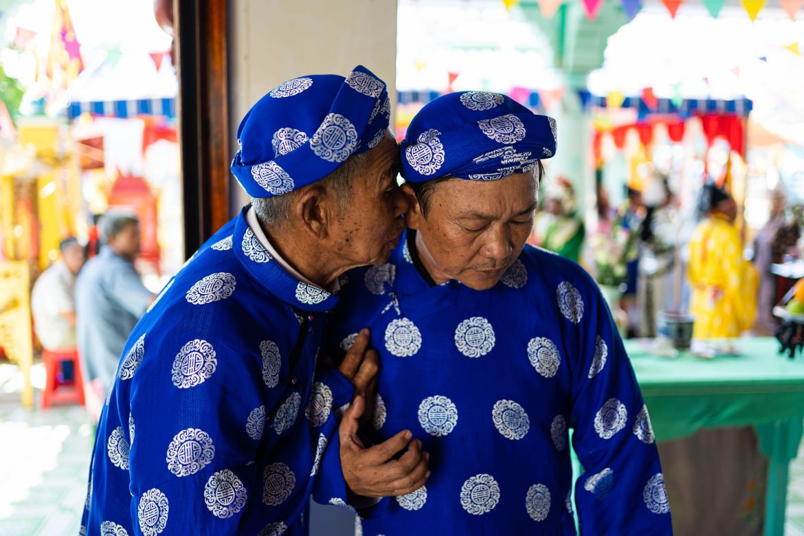 A photo of two worshippers dressed in traditional áo dài speaking in hushed tones during Phuoc Hai’s whale worship festival